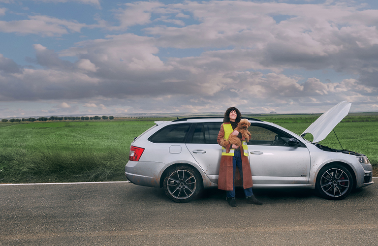 Frau mit Pannenweste und Hund vor Auto